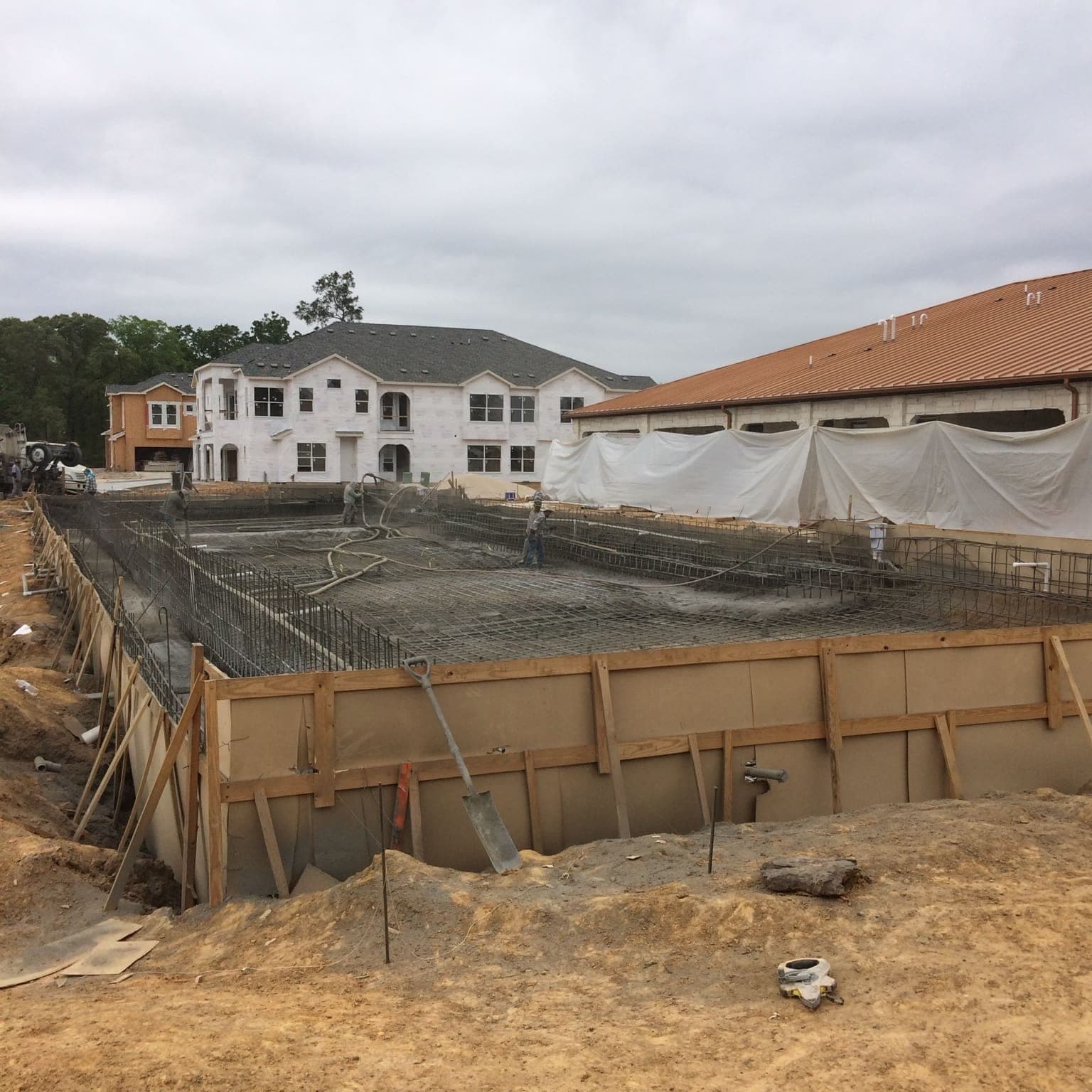 Large-scale commercial pool shotcrete in progress with apartment buildings visible in background