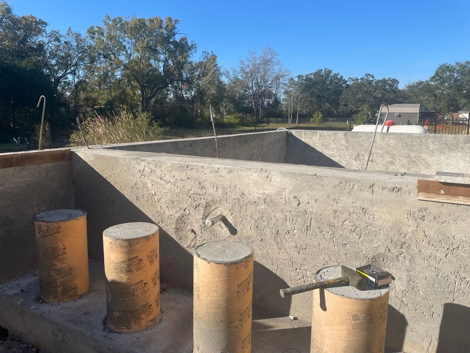 Close-up of fresh rectangular pool shell with plumbing stub-outs and cardboard tube forms
