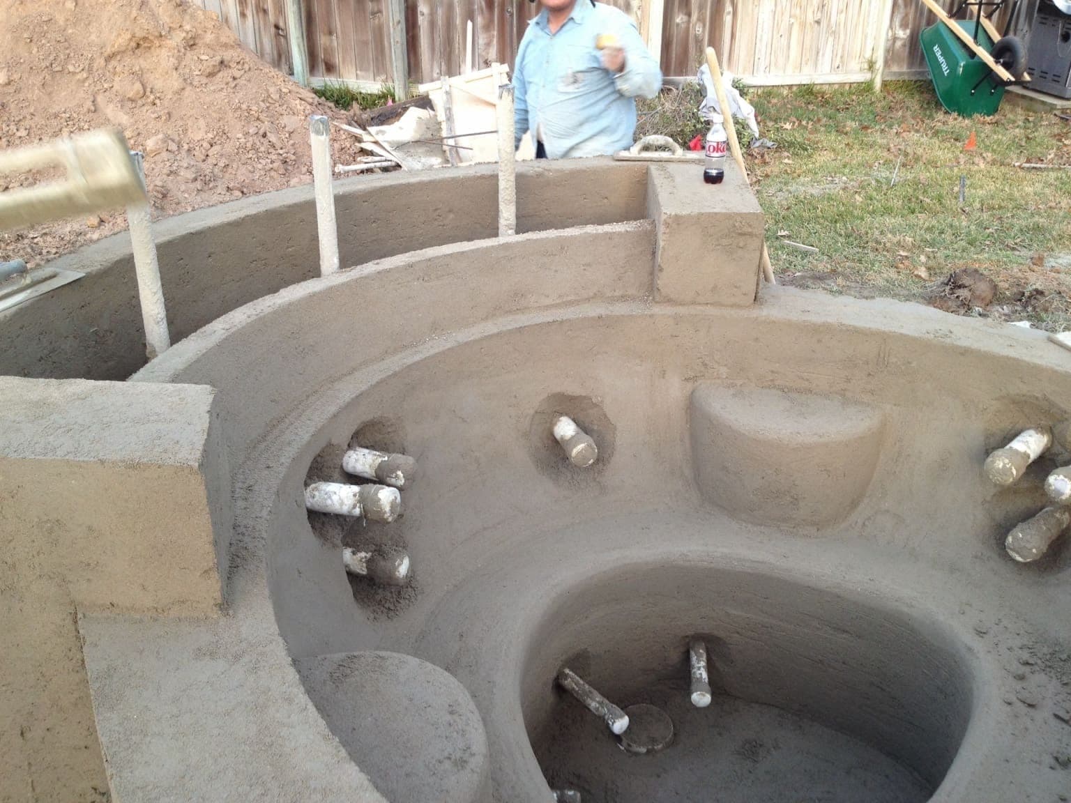 Freshly shot circular spa shell with plumbing stub-outs and rebar, viewed from above