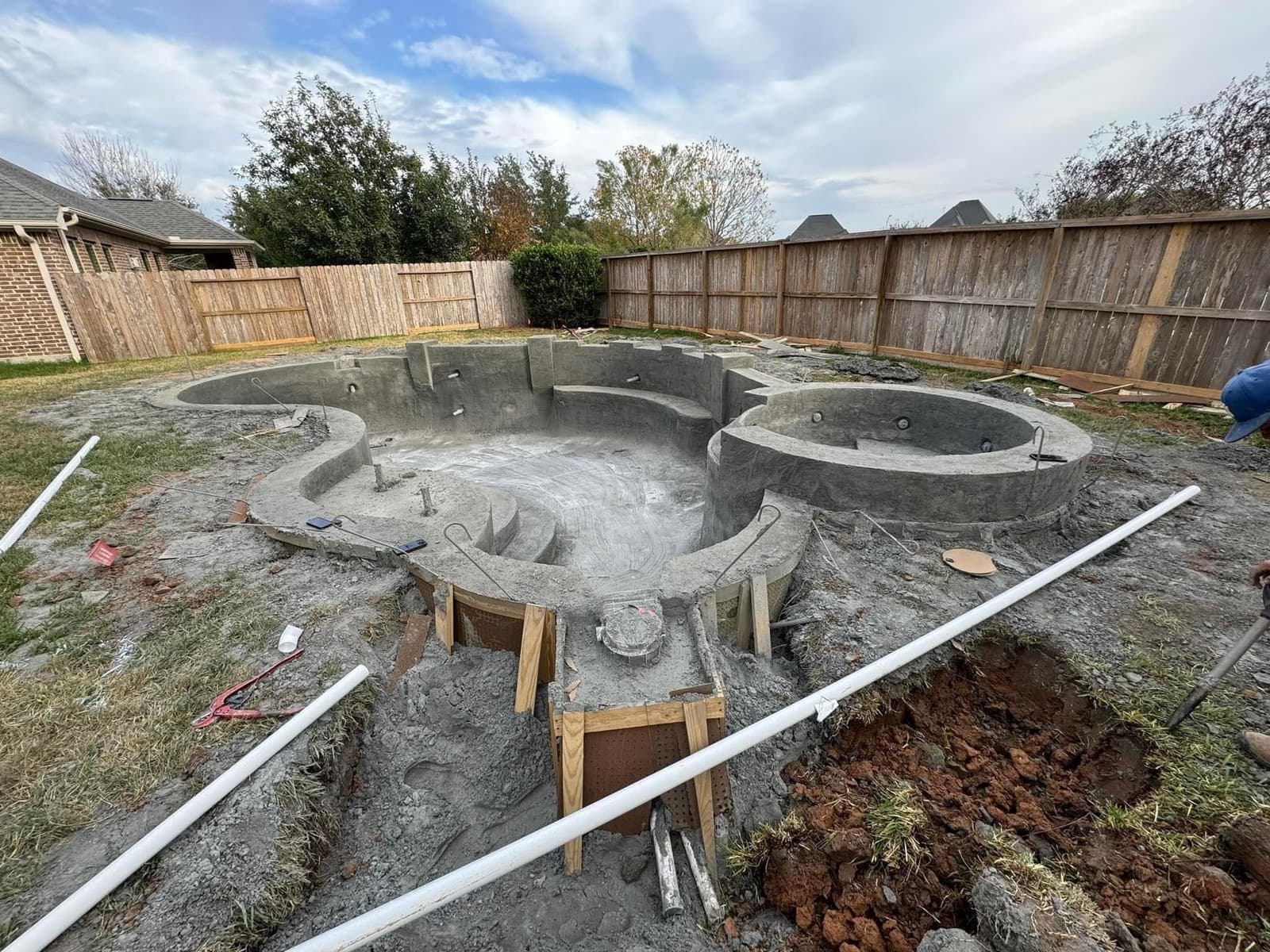 Freshly shot gunite pool shell with steps and bench in a Houston backyard